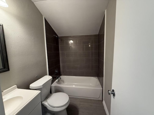 full bathroom featuring vanity, toilet, tiled shower / bath combo, and vaulted ceiling