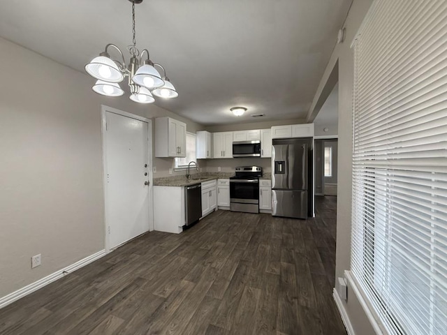 kitchen featuring appliances with stainless steel finishes, sink, white cabinets, hanging light fixtures, and dark wood-type flooring