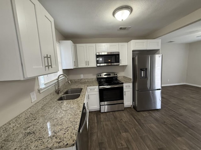 kitchen with sink, dark wood-type flooring, white cabinetry, stainless steel appliances, and light stone countertops