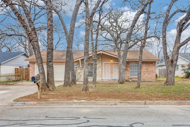 ranch-style home with brick siding, an attached garage, driveway, and fence