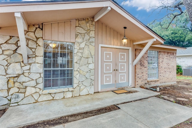 view of exterior entry featuring central air condition unit and stone siding