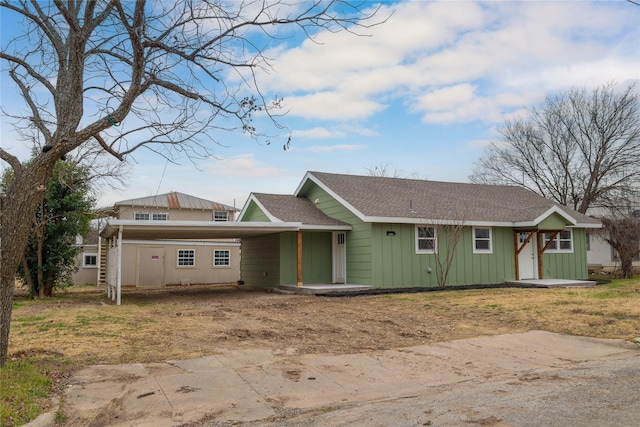 single story home featuring an attached carport, board and batten siding, and roof with shingles