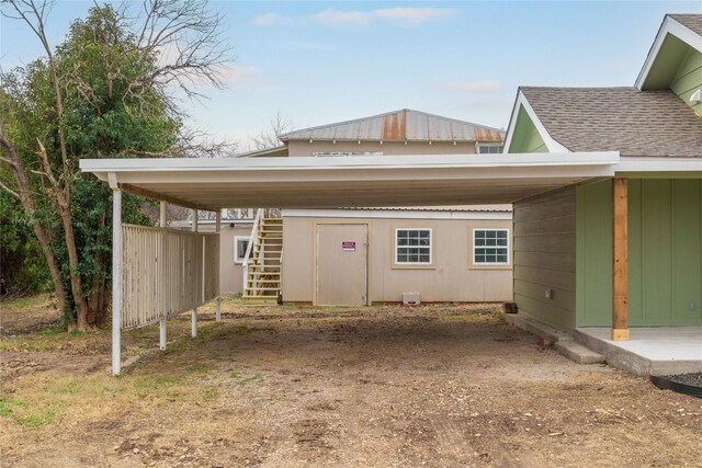 exterior space with stairway, an attached carport, and roof with shingles