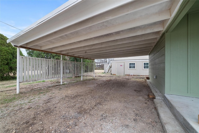 view of parking / parking lot with a carport, stairway, and fence