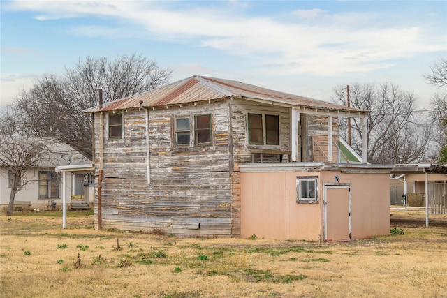 view of home's exterior featuring an outbuilding, a yard, and metal roof