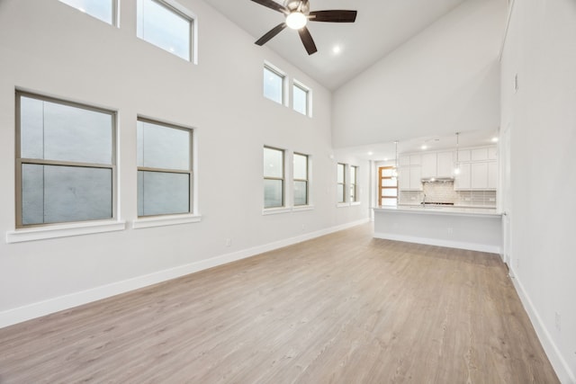 unfurnished living room with light hardwood / wood-style flooring, high vaulted ceiling, and ceiling fan