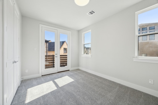 spare room featuring light colored carpet and french doors