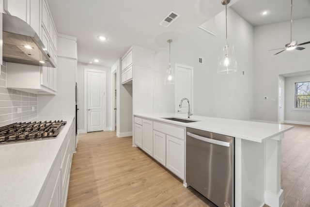 kitchen featuring sink, stainless steel appliances, white cabinets, decorative light fixtures, and light wood-type flooring