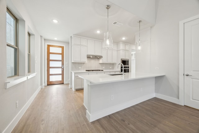 kitchen with white cabinetry, backsplash, sink, and pendant lighting