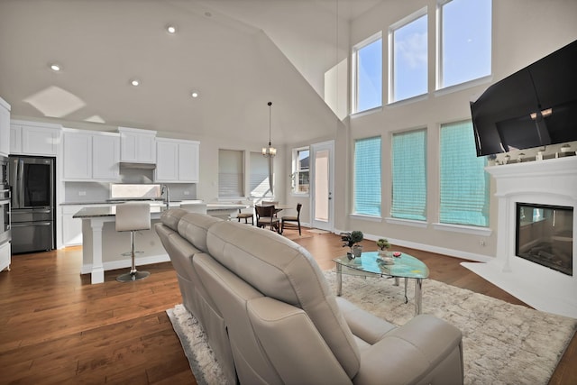 living room with dark hardwood / wood-style flooring, sink, and a high ceiling