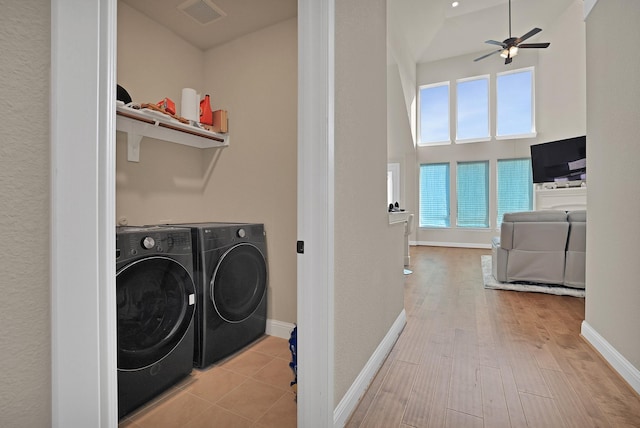 laundry area with ceiling fan, a towering ceiling, washer and clothes dryer, and light hardwood / wood-style floors