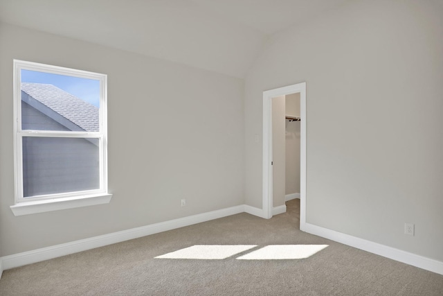 carpeted empty room with vaulted ceiling