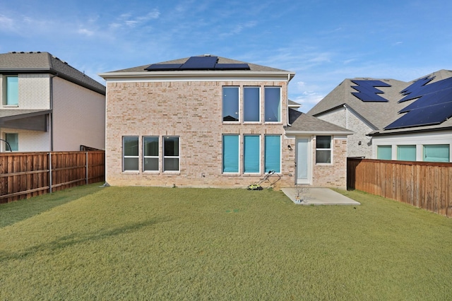 rear view of house featuring a yard and solar panels