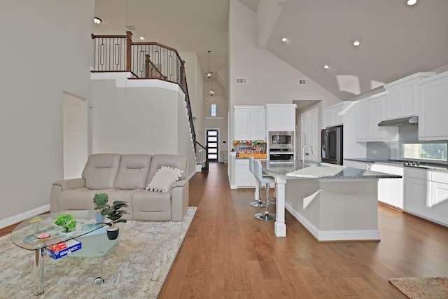 living room featuring sink, high vaulted ceiling, and light wood-type flooring