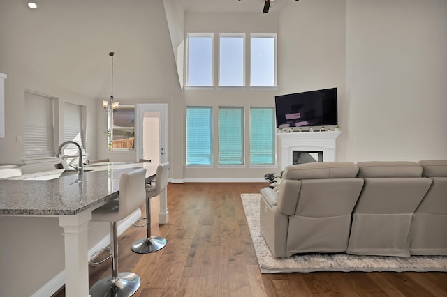 living room featuring sink, a wealth of natural light, light hardwood / wood-style floors, and a towering ceiling