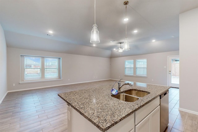 kitchen featuring decorative light fixtures, dishwasher, white cabinetry, sink, and a kitchen island with sink