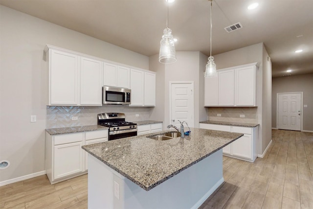 kitchen with stainless steel appliances, a kitchen island with sink, sink, and white cabinets