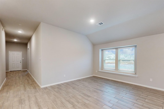 unfurnished room featuring lofted ceiling and light hardwood / wood-style flooring