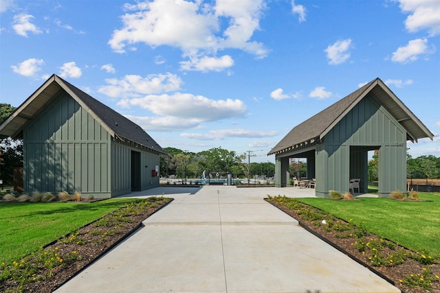 view of home's community with an outbuilding, a lawn, and a patio area