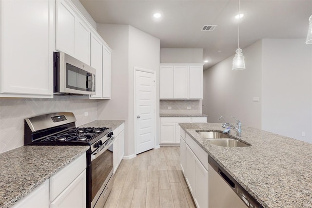 kitchen with pendant lighting, white cabinetry, appliances with stainless steel finishes, and light stone countertops