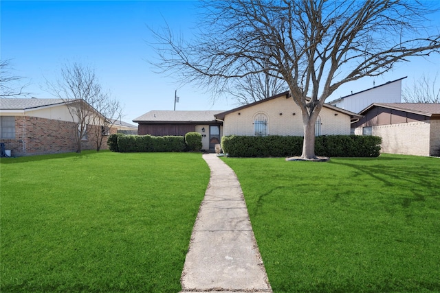 back of property with a yard, brick siding, and fence