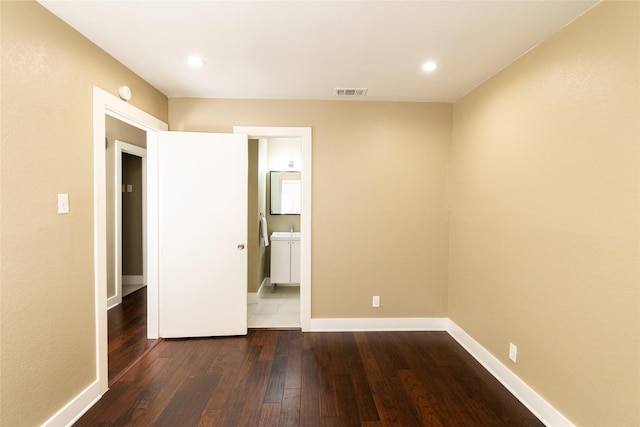 unfurnished bedroom featuring ensuite bath and dark hardwood / wood-style floors