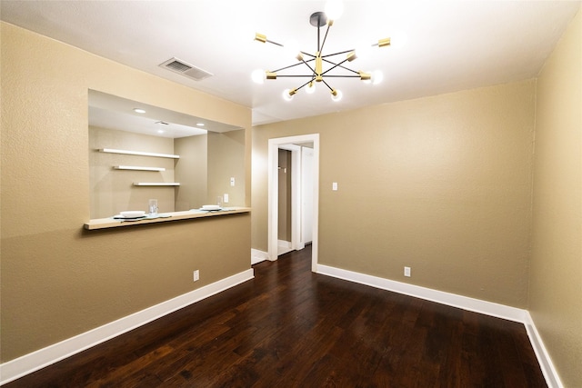 empty room featuring wood-type flooring and a notable chandelier