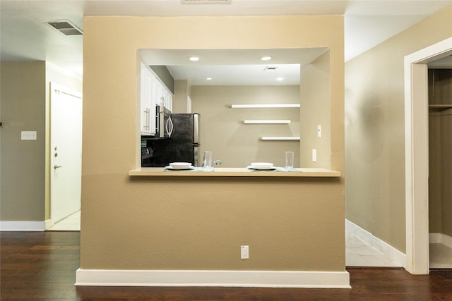 kitchen with stainless steel appliances, dark wood-type flooring, white cabinets, and kitchen peninsula