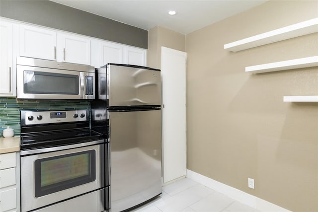 kitchen featuring decorative backsplash, light tile patterned flooring, white cabinets, and appliances with stainless steel finishes