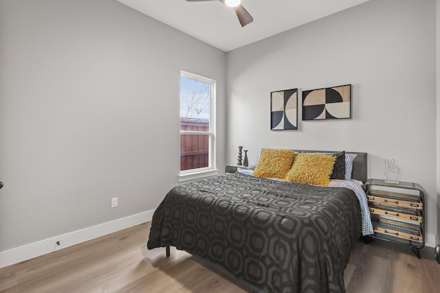 bedroom featuring a ceiling fan, baseboards, and wood finished floors