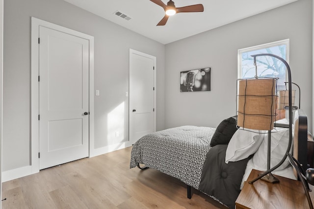 bedroom with light wood-type flooring, baseboards, visible vents, and ceiling fan