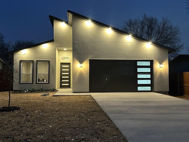 contemporary home with driveway, an attached garage, and stucco siding