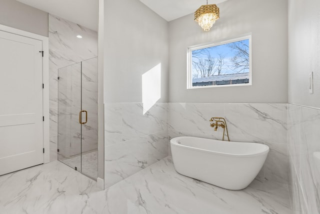 bathroom featuring a wainscoted wall, tile walls, marble finish floor, a soaking tub, and a marble finish shower