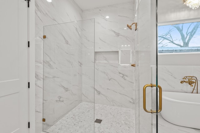 full bath featuring a freestanding bath and a marble finish shower