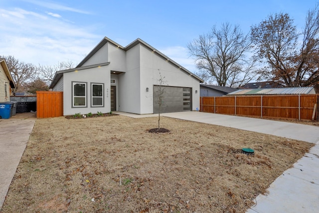 view of front of house featuring a garage, concrete driveway, fence, and stucco siding