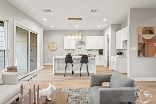 living area with light wood-style flooring, recessed lighting, visible vents, and baseboards