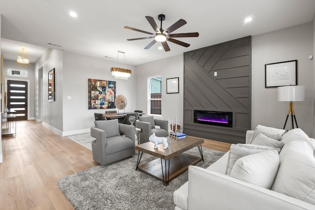 living area with light wood-type flooring, a large fireplace, baseboards, and recessed lighting