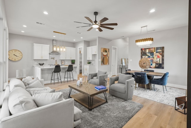 living area with recessed lighting, visible vents, ceiling fan, light wood-type flooring, and baseboards