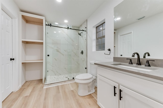 bathroom with vanity, wood-type flooring, a shower with shower door, and toilet