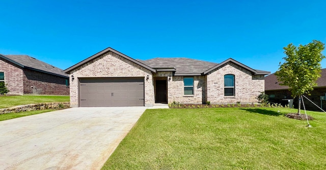 view of front facade with a front yard, concrete driveway, brick siding, and an attached garage