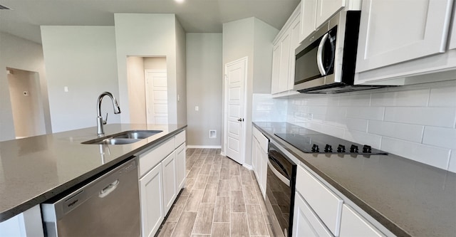 kitchen featuring tasteful backsplash, appliances with stainless steel finishes, wood tiled floor, white cabinets, and a sink