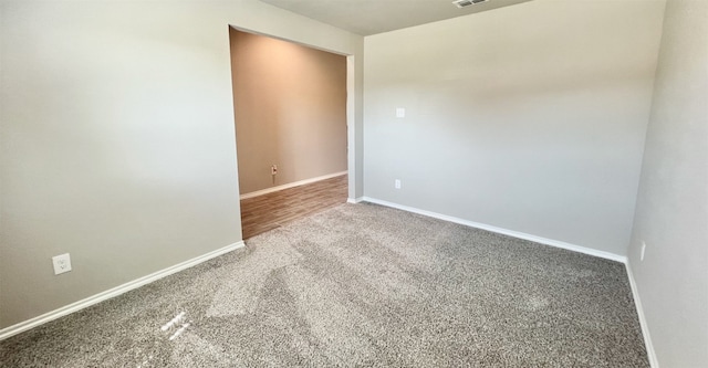 unfurnished room with carpet floors, visible vents, and baseboards