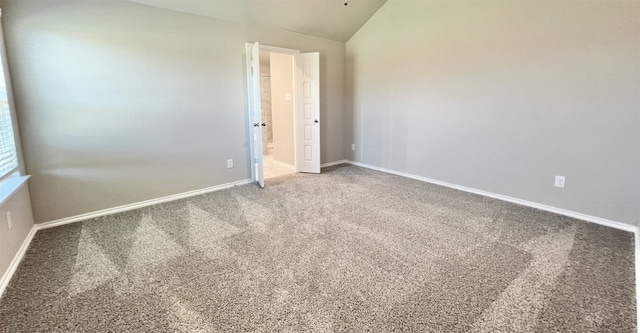 carpeted spare room with lofted ceiling and baseboards