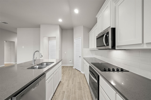 kitchen with stainless steel appliances, visible vents, backsplash, a sink, and light wood-type flooring