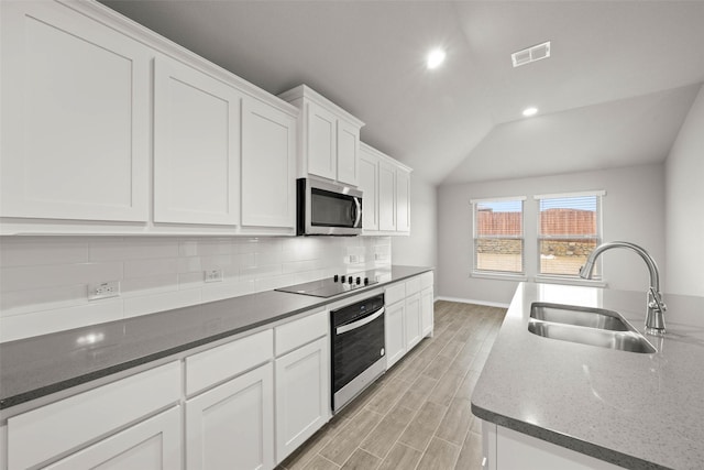 kitchen with visible vents, backsplash, appliances with stainless steel finishes, wood tiled floor, and a sink