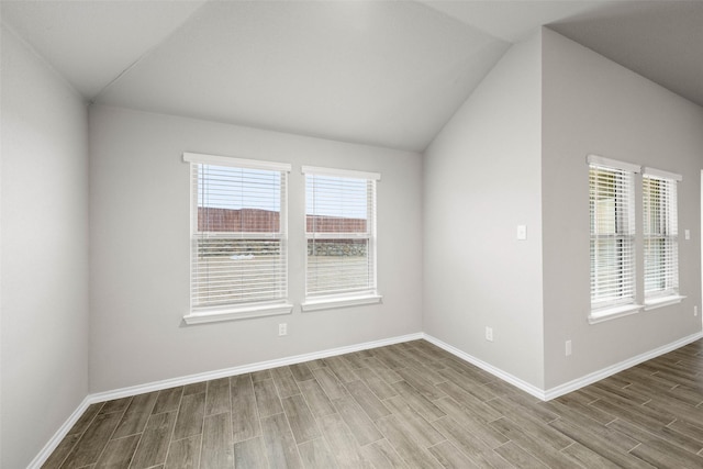 empty room with wood tiled floor, lofted ceiling, and baseboards