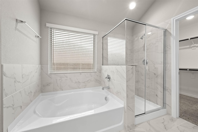 bathroom with marble finish floor, a spacious closet, a shower stall, and a bath