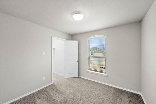 spare room featuring baseboards and light colored carpet