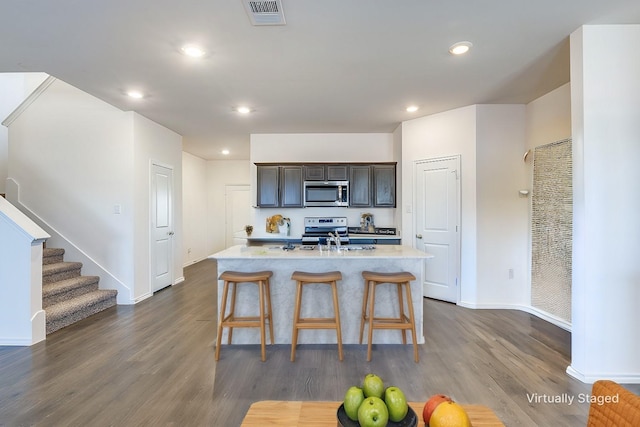 kitchen with visible vents, light countertops, appliances with stainless steel finishes, dark wood-style floors, and a kitchen bar