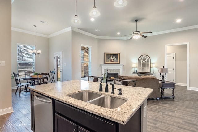 kitchen featuring a kitchen island with sink, sink, decorative light fixtures, and light stone countertops